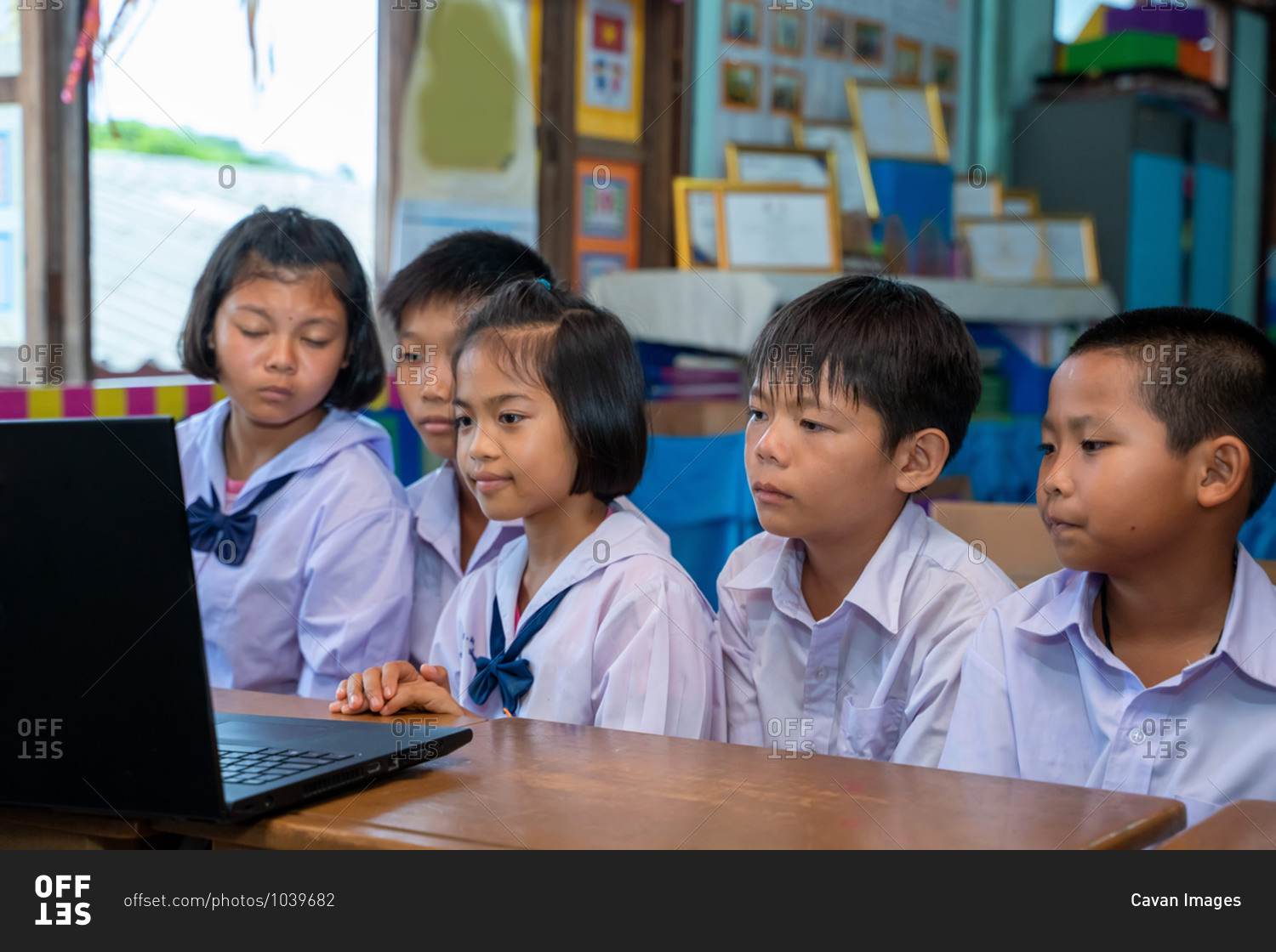 Elementary school students looking at computer in classroom