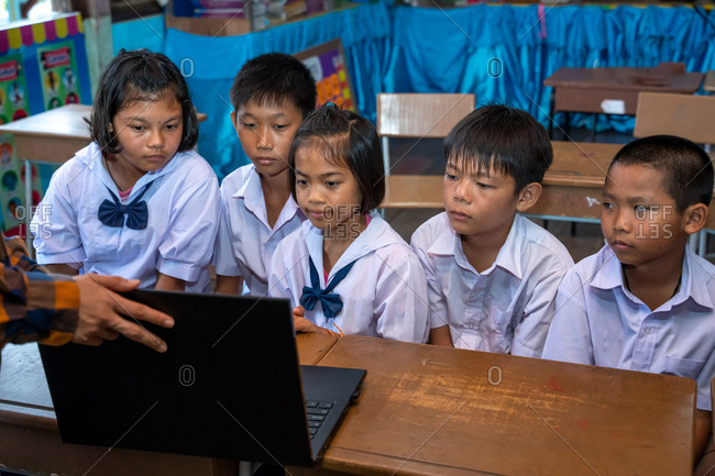 Group of Asian elementary school students learning to use laptops