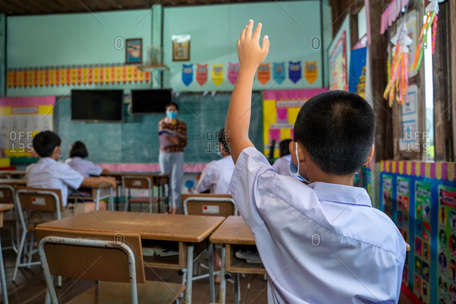 Asian student raises hand in classroom