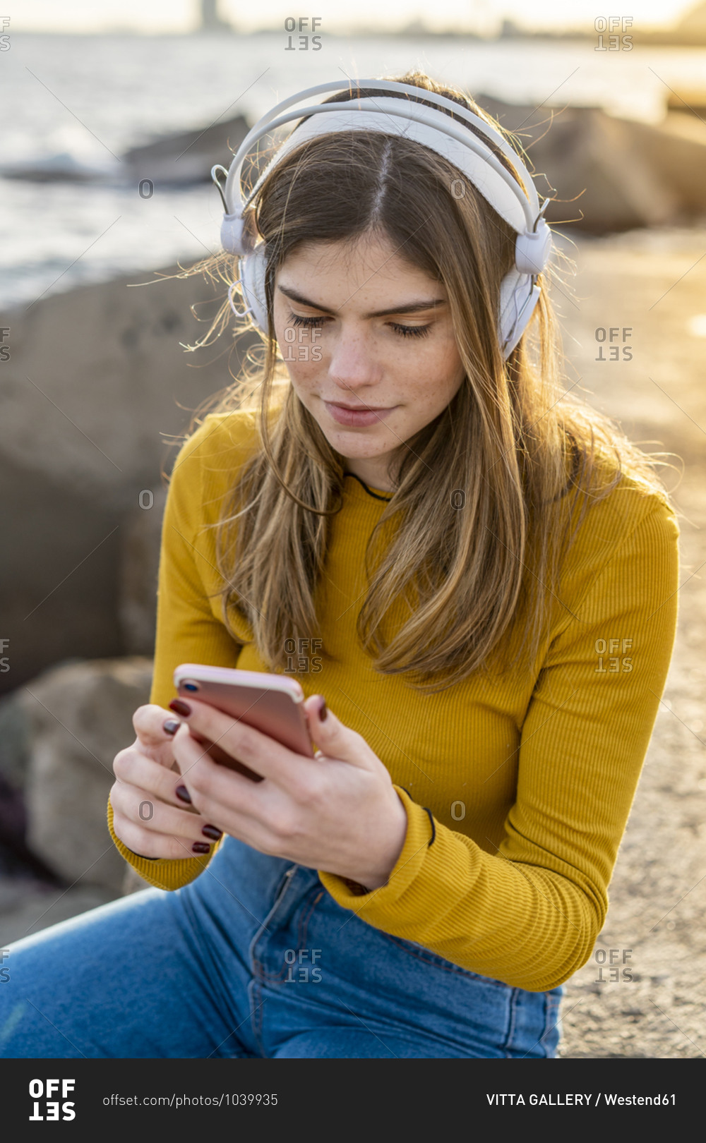 Thoughtful woman with mobile phone listening to music in city