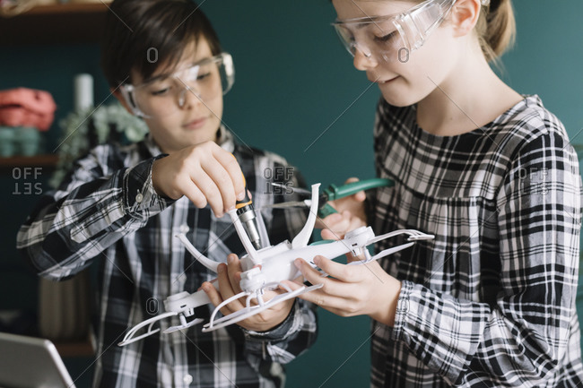 Close-up of siblings making drone at home