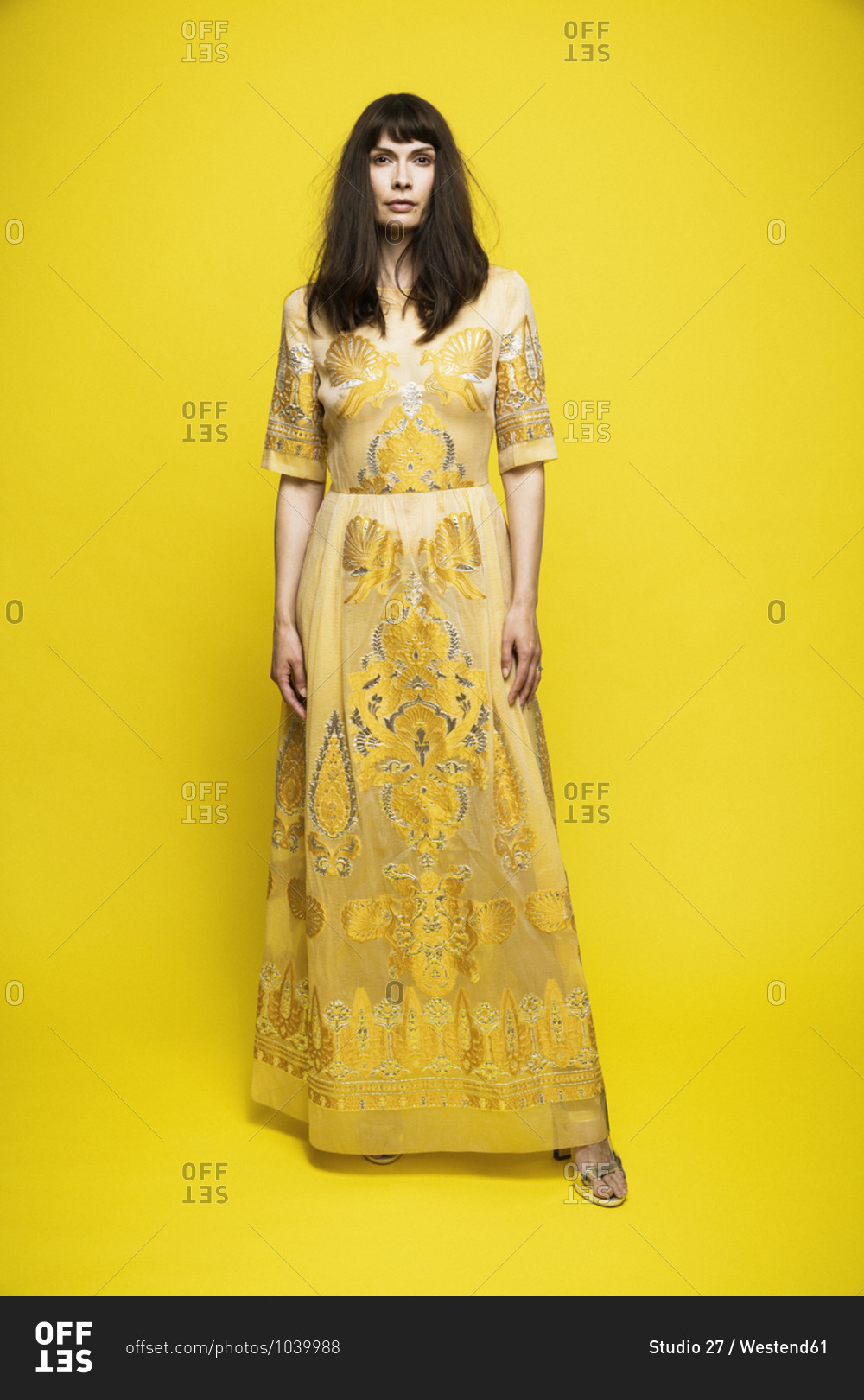 Mature woman wearing dress standing against yellow background