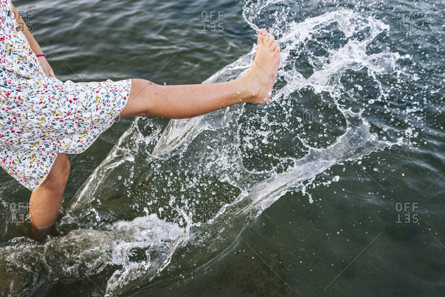 Girl splashing water with legs in lake