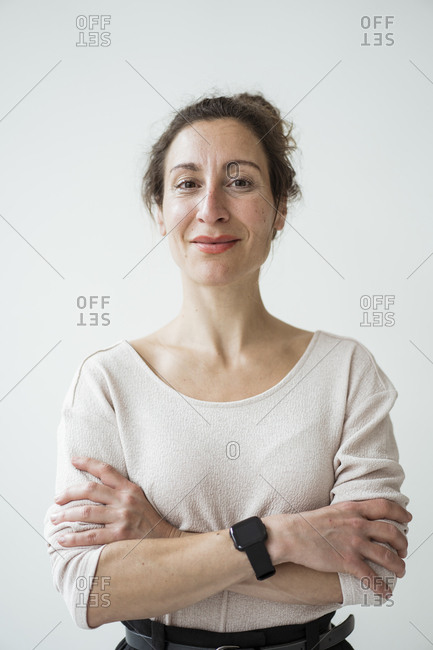 Close-up of smiling female entrepreneur with arms crossed standing against wall