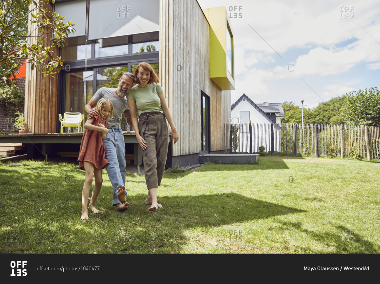 Cheerful parents with daughter standing against tiny house in yard