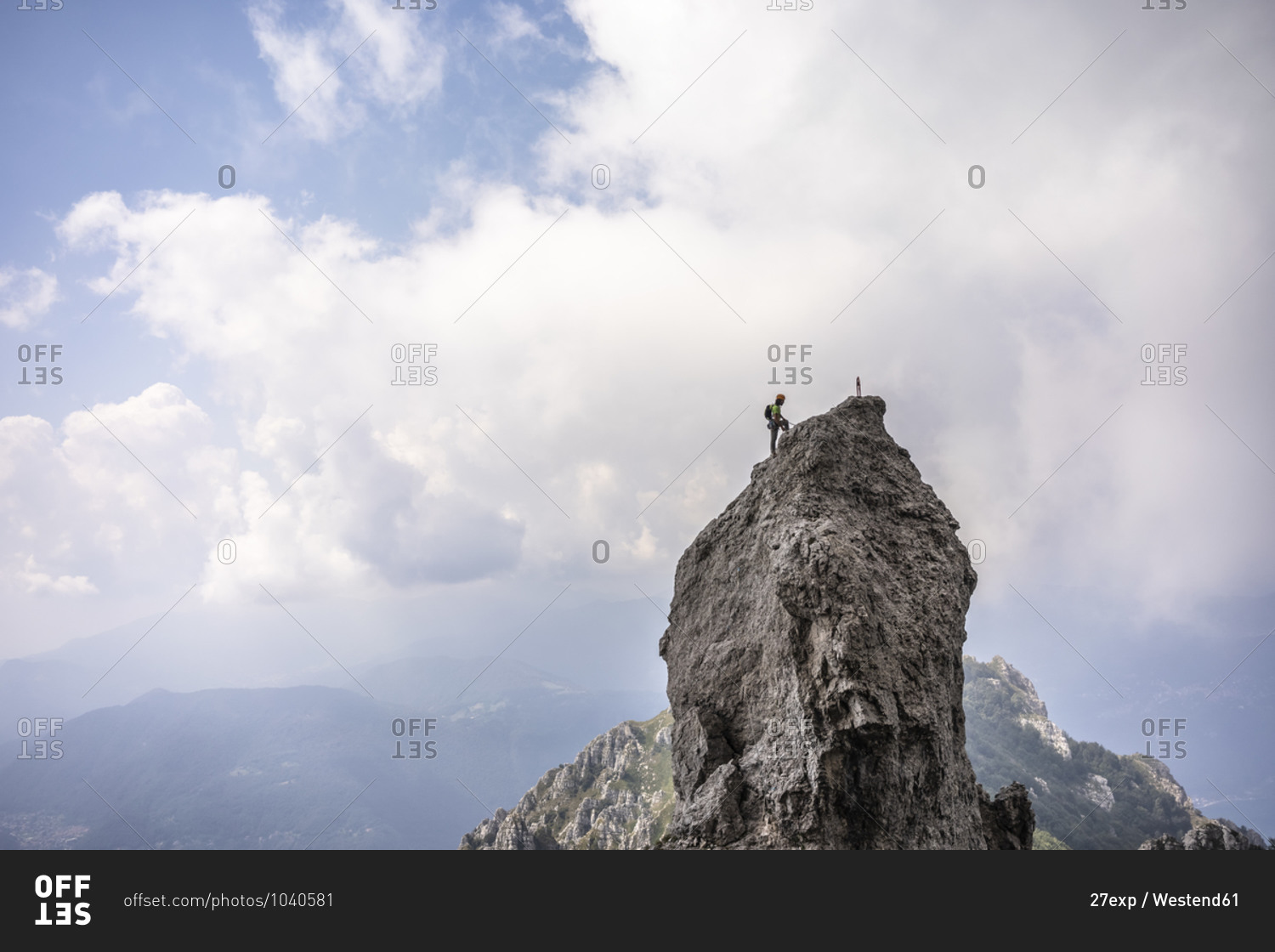Male hiker standing on top of mountain against cloudy sky- European Alps- Lecco- Italy