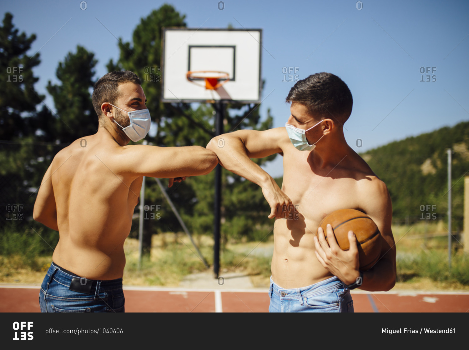 Athletes with face mask greeting with elbow bump at basketball court