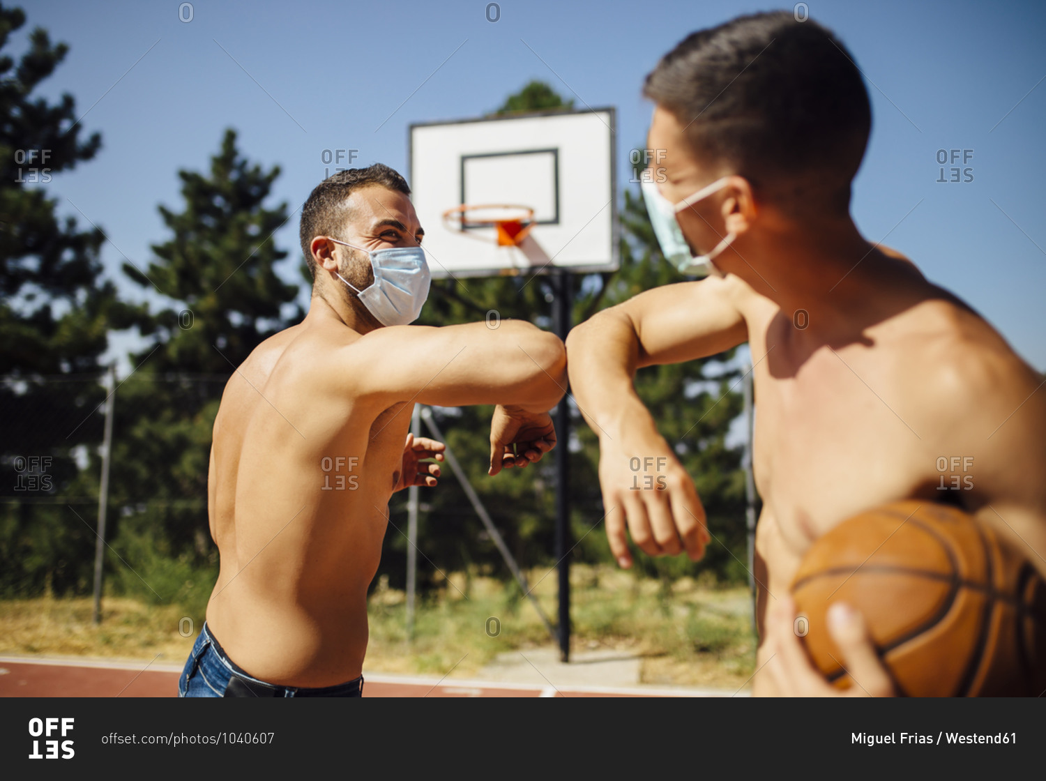 Men with face mask greeting with elbow bump at basketball court