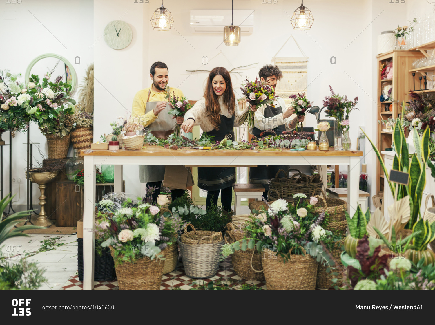 Florist team arranging flowers and plant while standing at flower shop