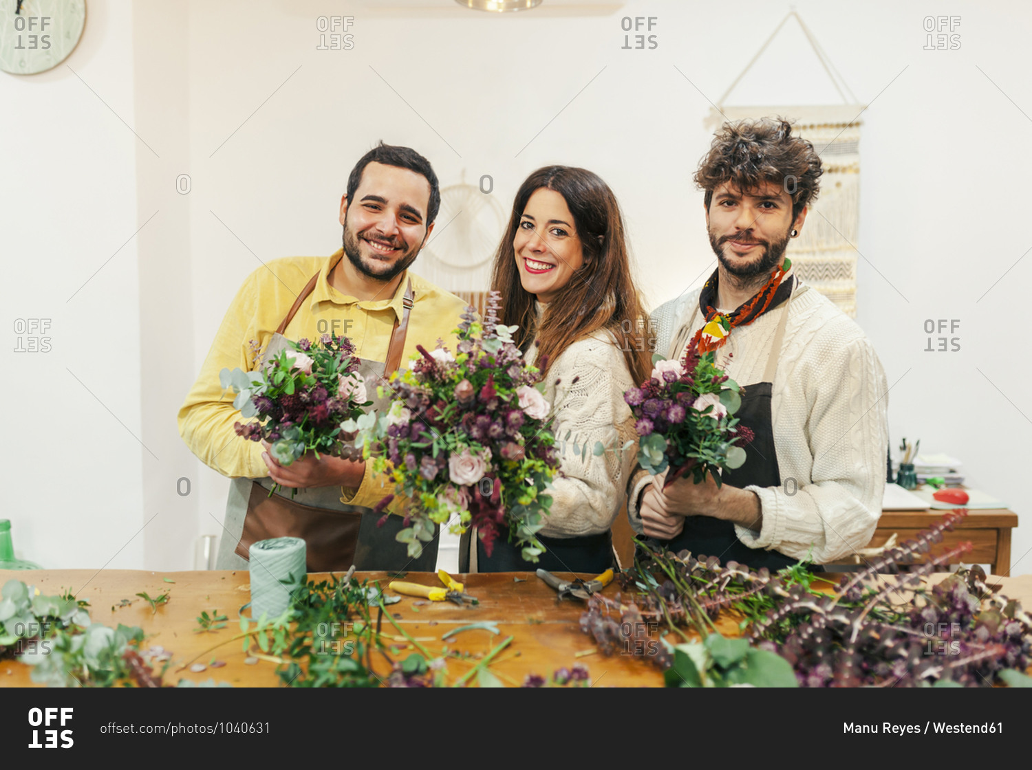 Florist team holding bouquet while standing by table flower shop