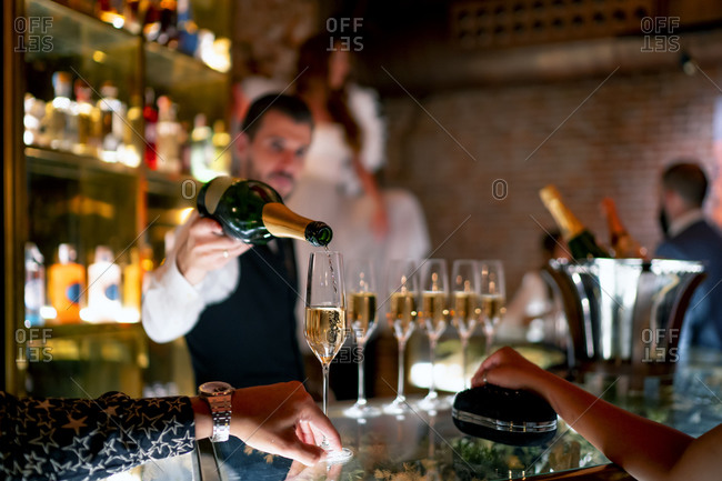 Bartender serving drink to man and woman at bar counter in pub