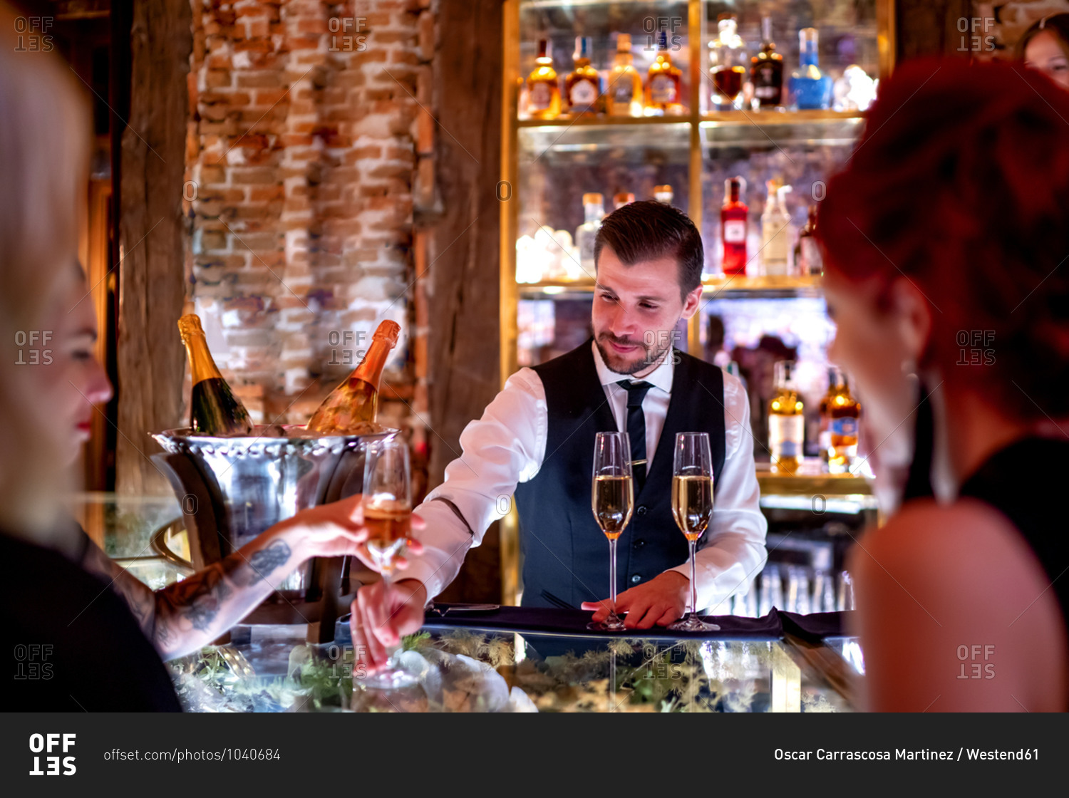 Bartender serving drink to women at bar counter in pub