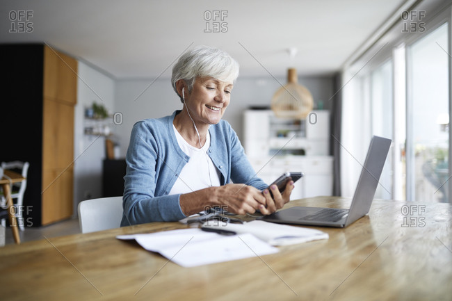 Active senior female listening to music while sitting at home