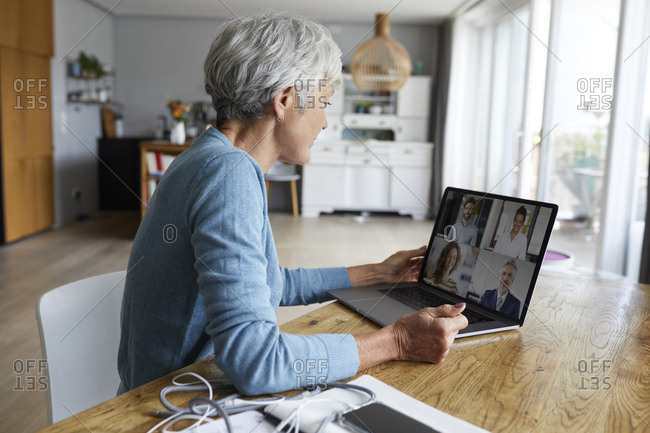 Active senior woman attending meeting on video conference while sitting at home