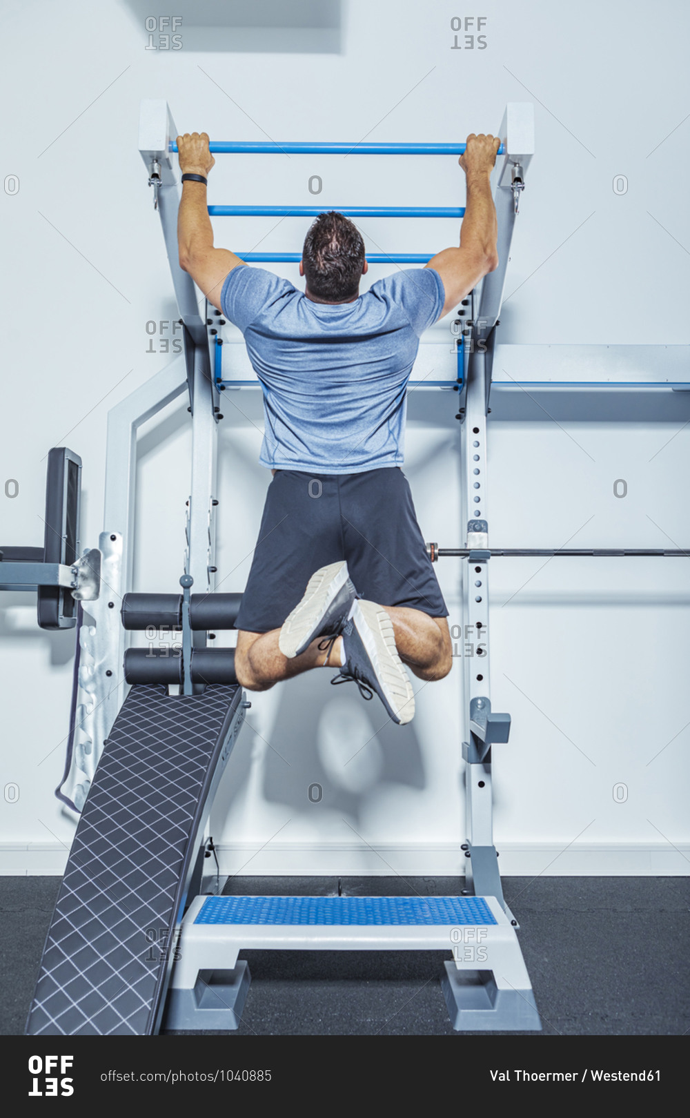 Male athlete exercising on chin-ups bars in gym
