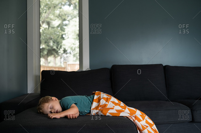 Blonde toddler boy passed out on living room sofa