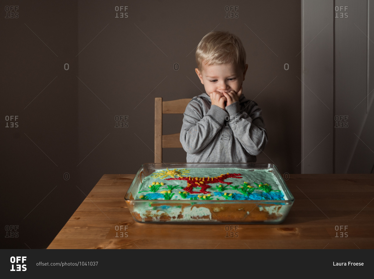 Excited little boy looking down at his homemade dinosaur cake