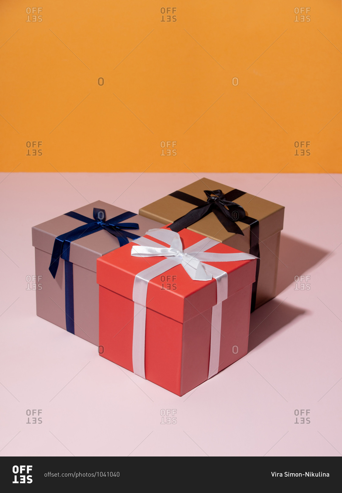 Three holiday boxes on a pink table and yellow background