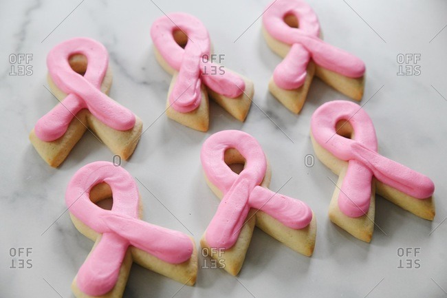 Pink ribbon shaped cookies with icing in representation of Breast Cancer Awareness on a marble surface