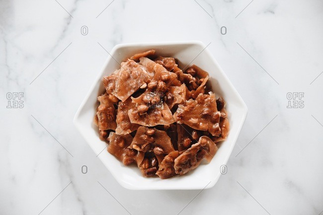 Overhead view of peanut brittle pieces in a white dish