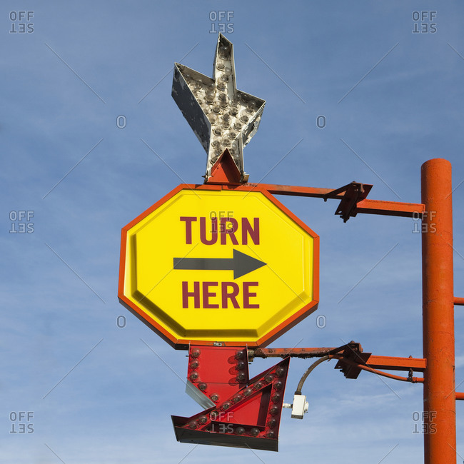 Turn Here, yellow traffic sign with arrow, on a gantry with a silver star shape