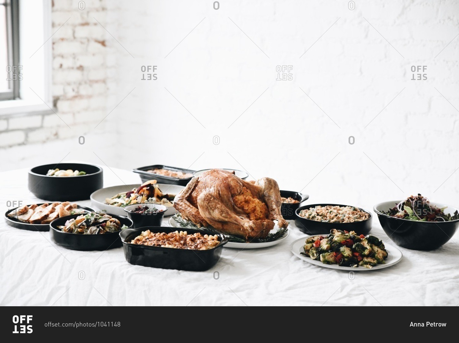 Traditional Thanksgiving dinner food served for a gathering\
on a table in front of white wall stock photo - OFFSET