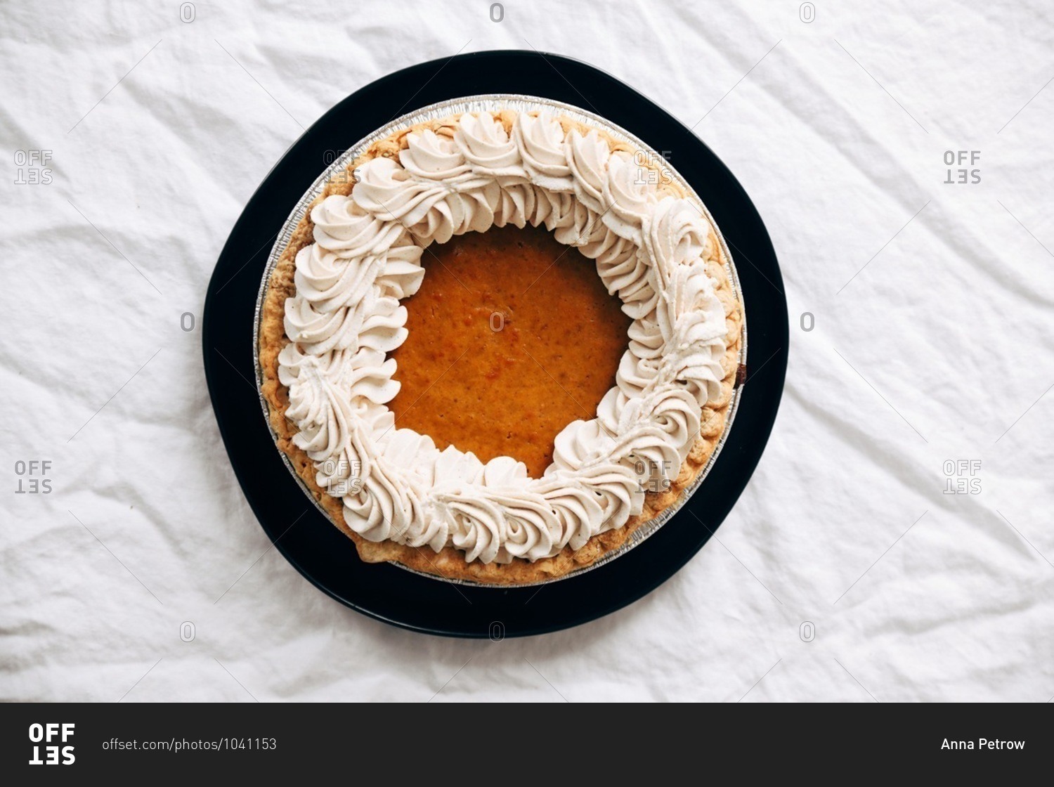 A whole pumpkin pie for Thanksgiving dessert on white linen tablecloth