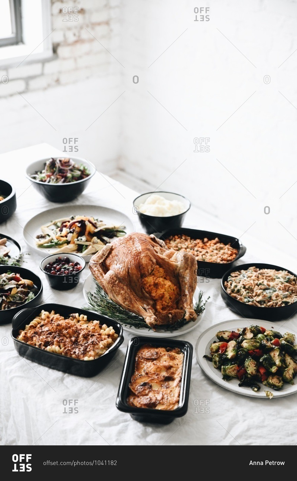 Holiday dinner with turkey and side dishes served on a table with white tablecloth