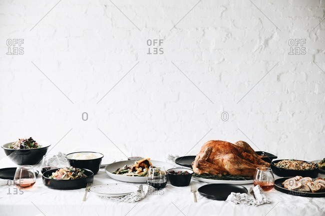 Thanksgiving turkey and side dishes served on a table in front of white texture wall
