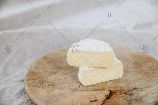 Soft white bloomy rind cheese on a wooden cutting board