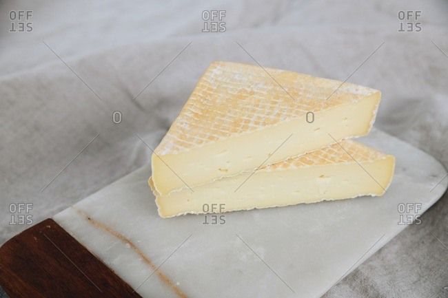 Triangles of bloomy rind cheese cut and stacked on marble