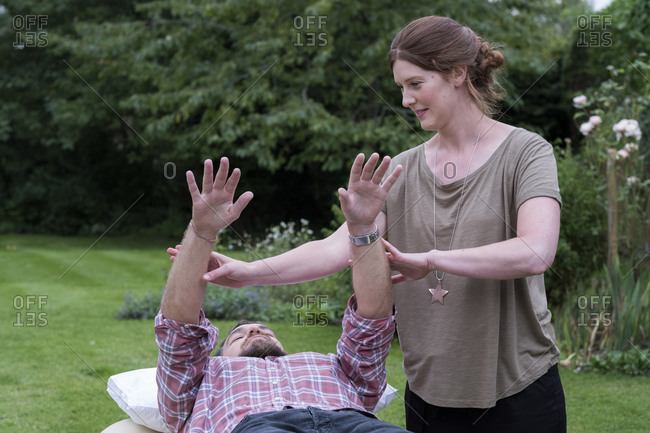 Man on a couch and therapist raising his arms in a garden therapy session