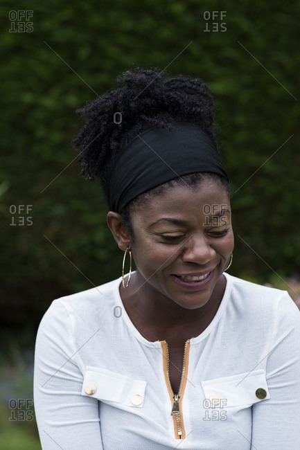 Portrait of black woman sitting in a garden, smiling during alternative therapy session.