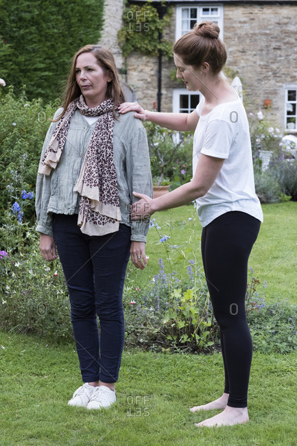Therapist focusing on the standing posture of a client in a garden.