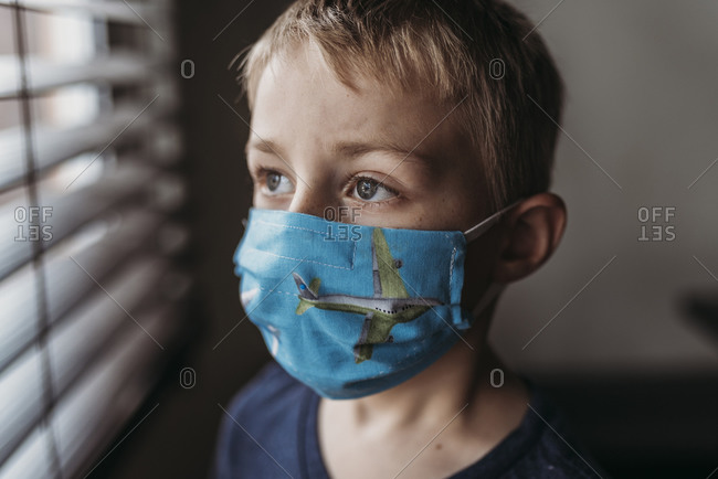 Portrait of young school aged boy with mask on with at home