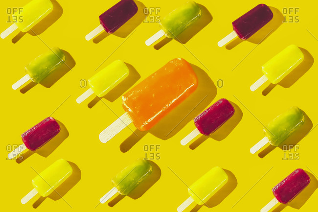 Bright and colorful fruit popsicles on yellow background