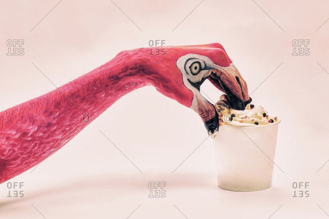 A hand painted like a flamingo diving into an ice-cream cup