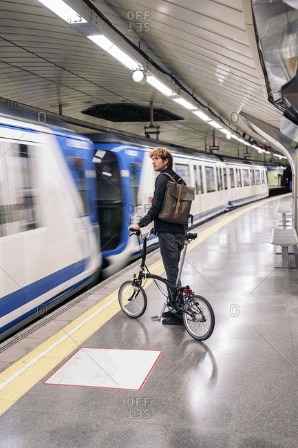 Young man in the metro holding his detachable bike.