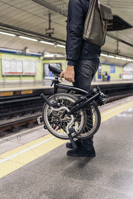 Unrecognized man in the metro holding his detachable bike.