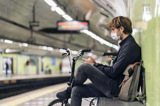 Young man sitting in the metro next to his detachable bike.