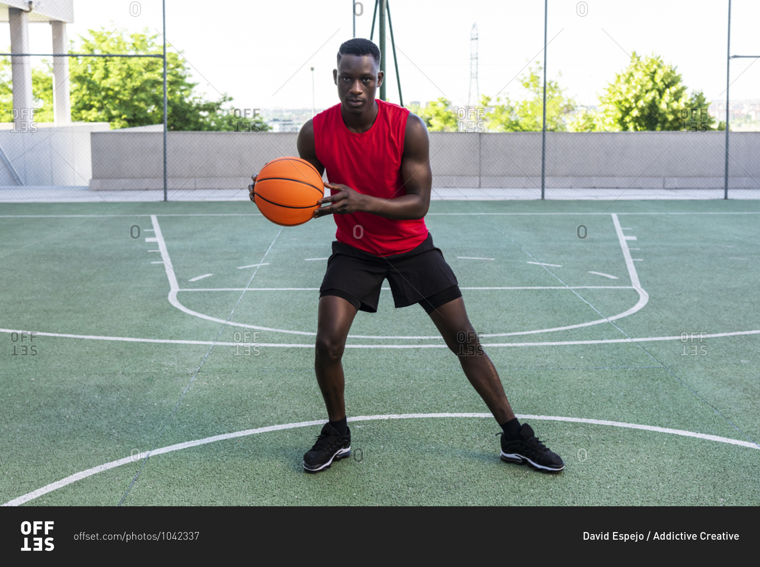 Serious African American male playing basketball on modern sports ground and looking at camera during training