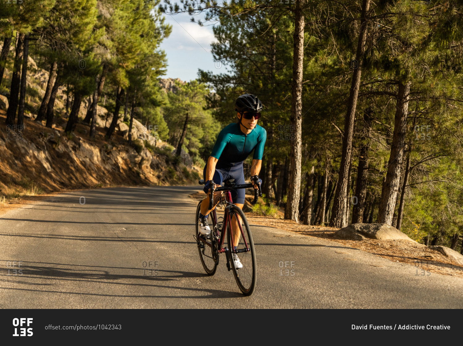 mature woman training road bike, climbing a mountain road, front view