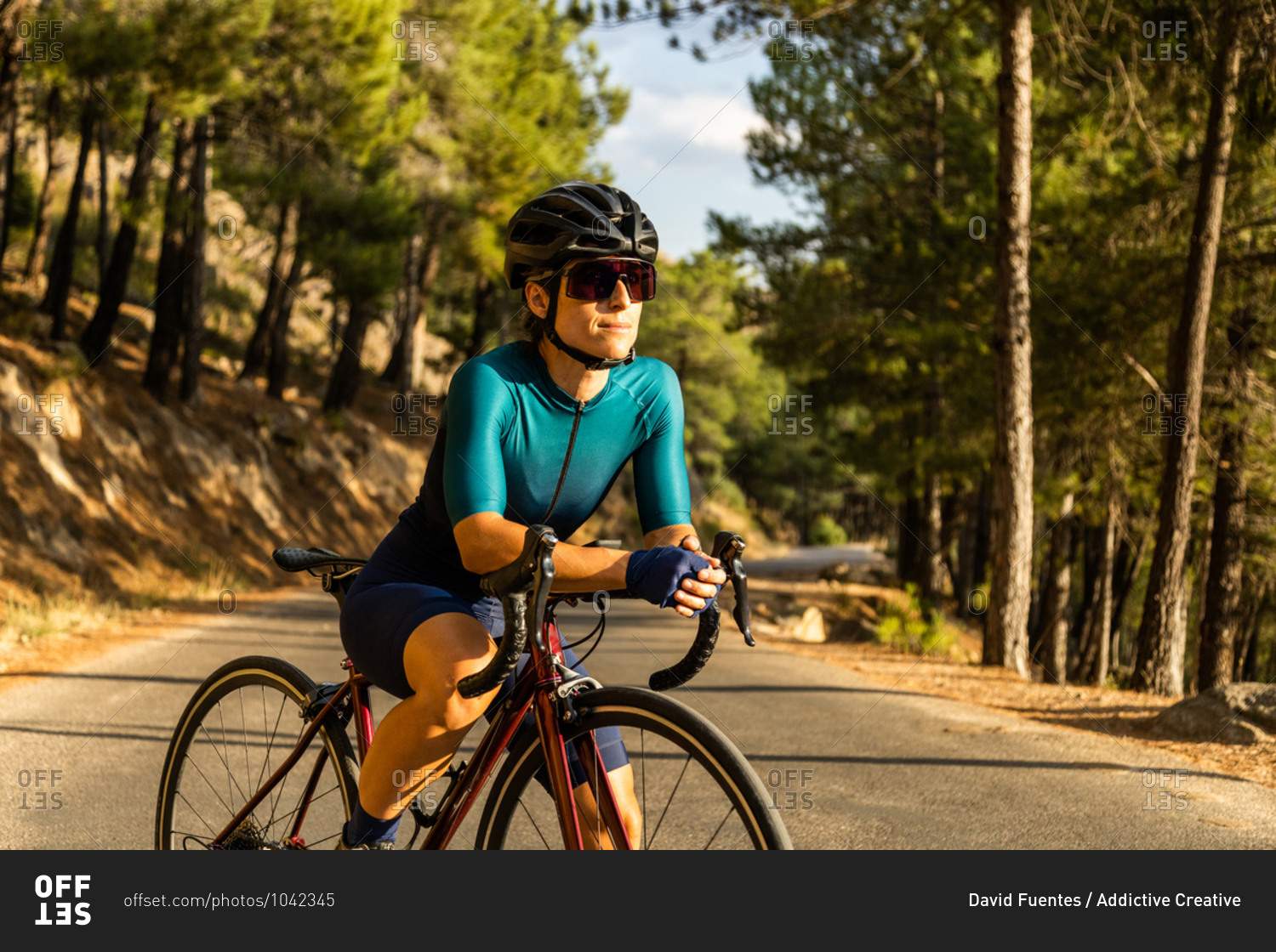 mature woman training road bike, climbing a mountain road, resting sit on the bike