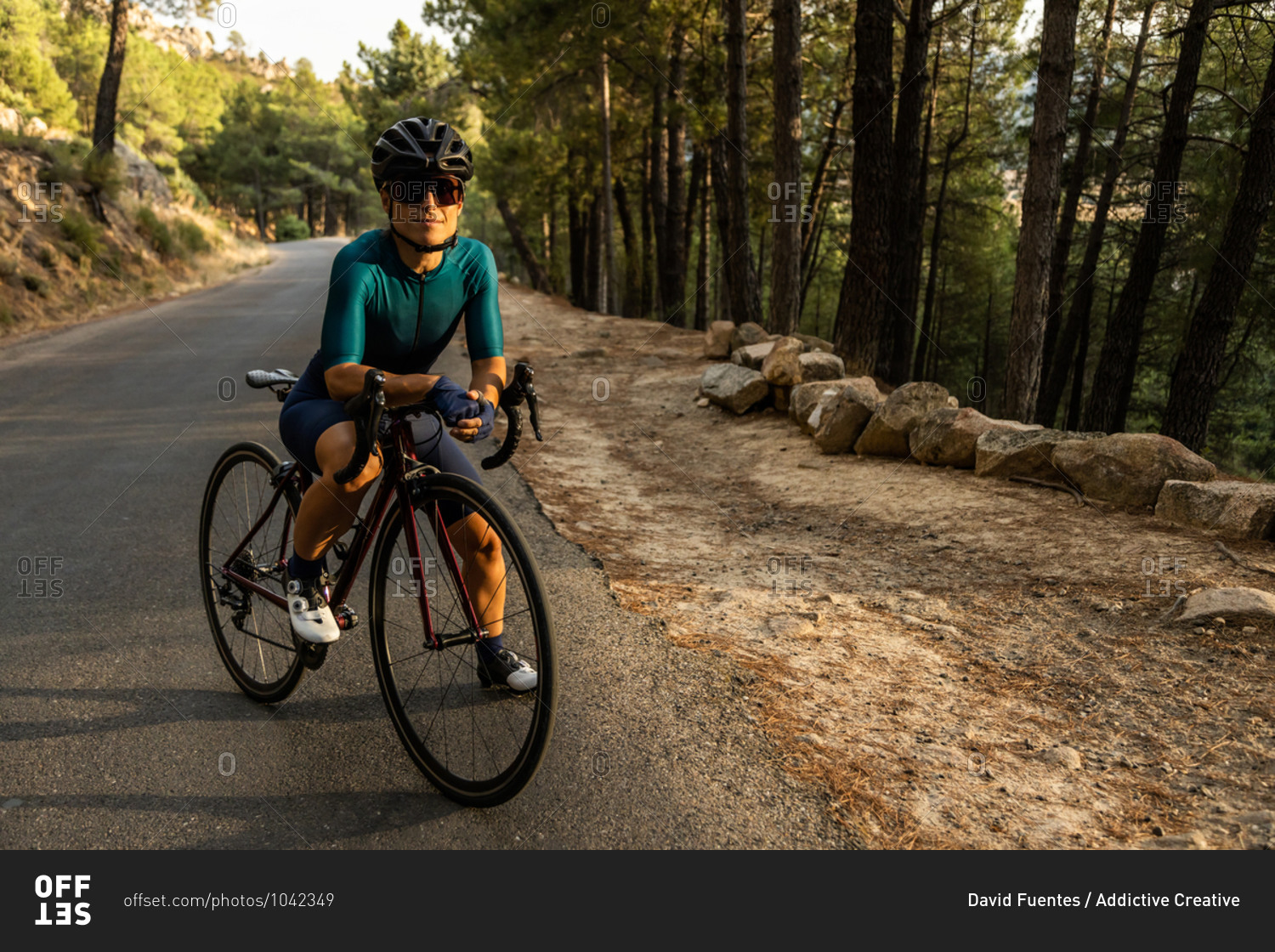 mature woman training road bike, climbing a mountain road, resting sit on the bike, front view