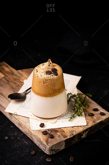 High angle of refreshing Dalgona coffee with whipped topping served on wooden board in cafe