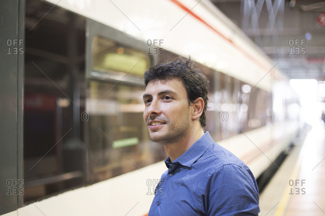 Young man with brown hair and blue shirt at train station