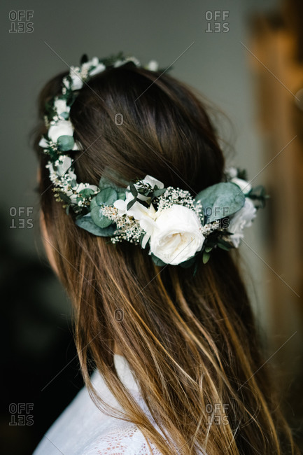Back view of anonymous female wearing tender wreath with white rose flowers standing in flat
