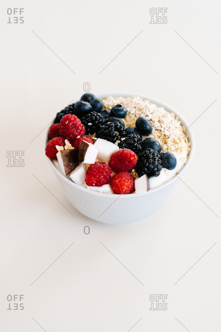 High angle of nutritious bowl with muesli and various berries in bowl placed on white table for breakfast in morning