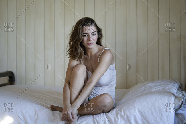 Beautiful young woman sitting on bed