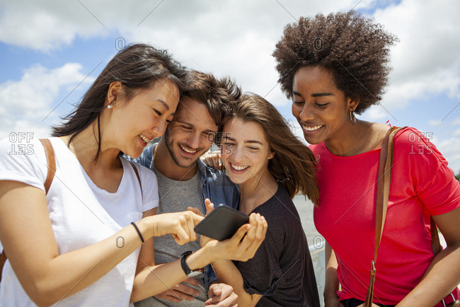 Happy young friends watching photos on smartphone